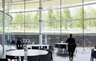 The modern canteen inside the McLaren Technology Centre, with tables and a view of the surrounding trees.