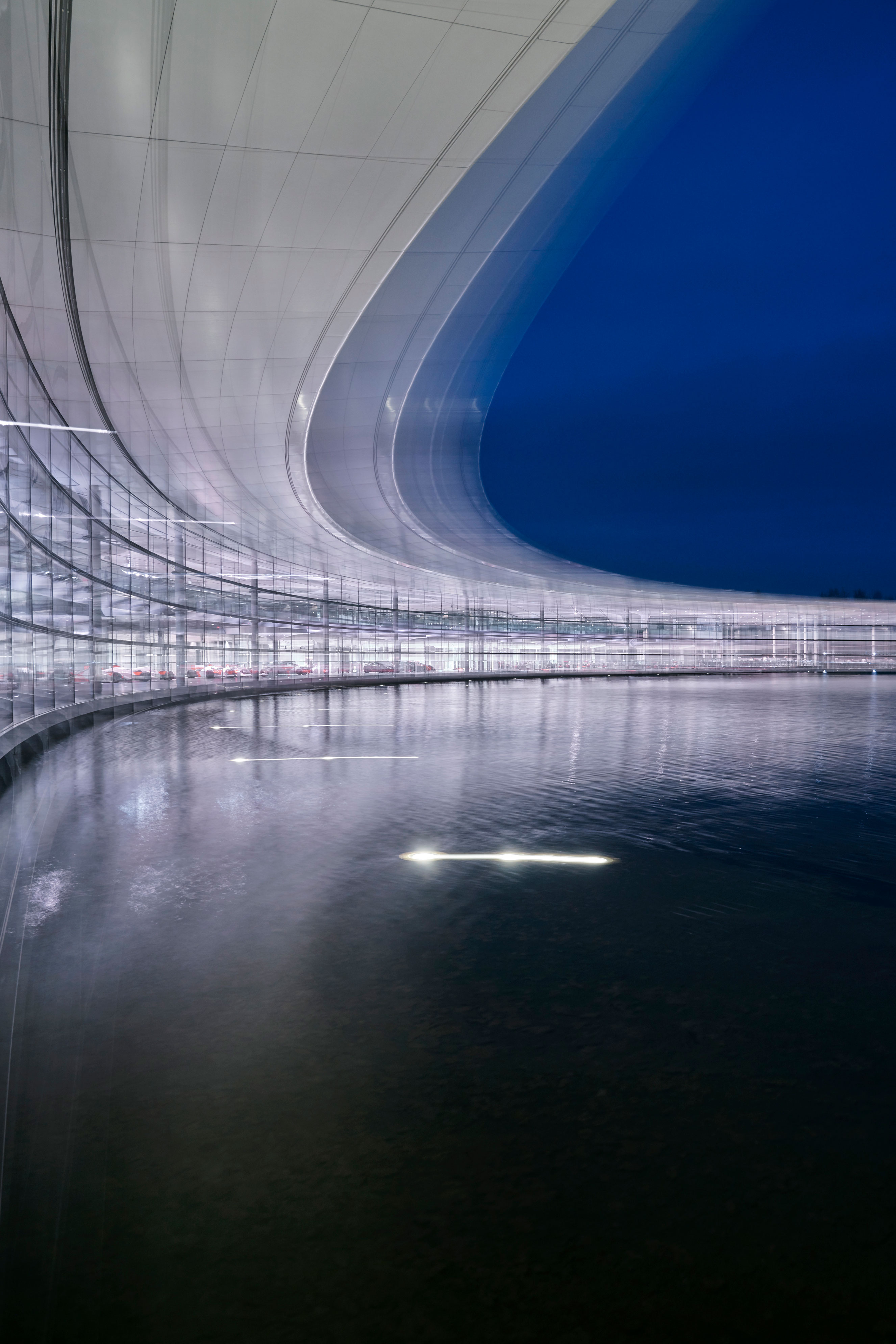 The McLaren Technology Centre at night, with its building reflected in a reflective lake.
