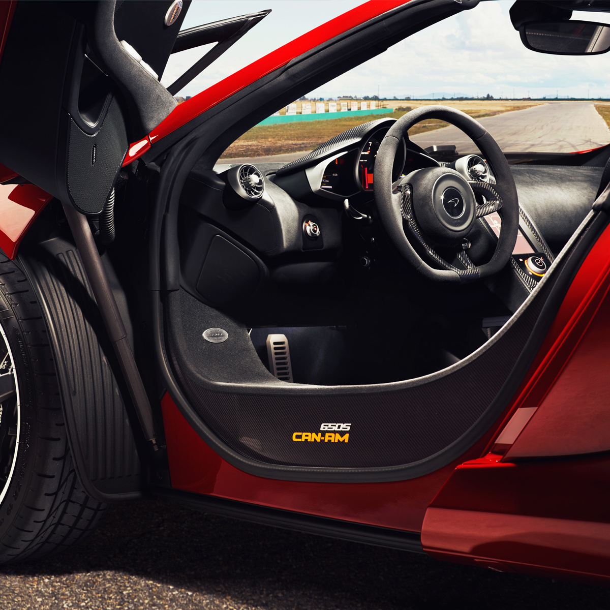 Interior of a red McLaren 650S CAN-AM Spider, parked on a race track.