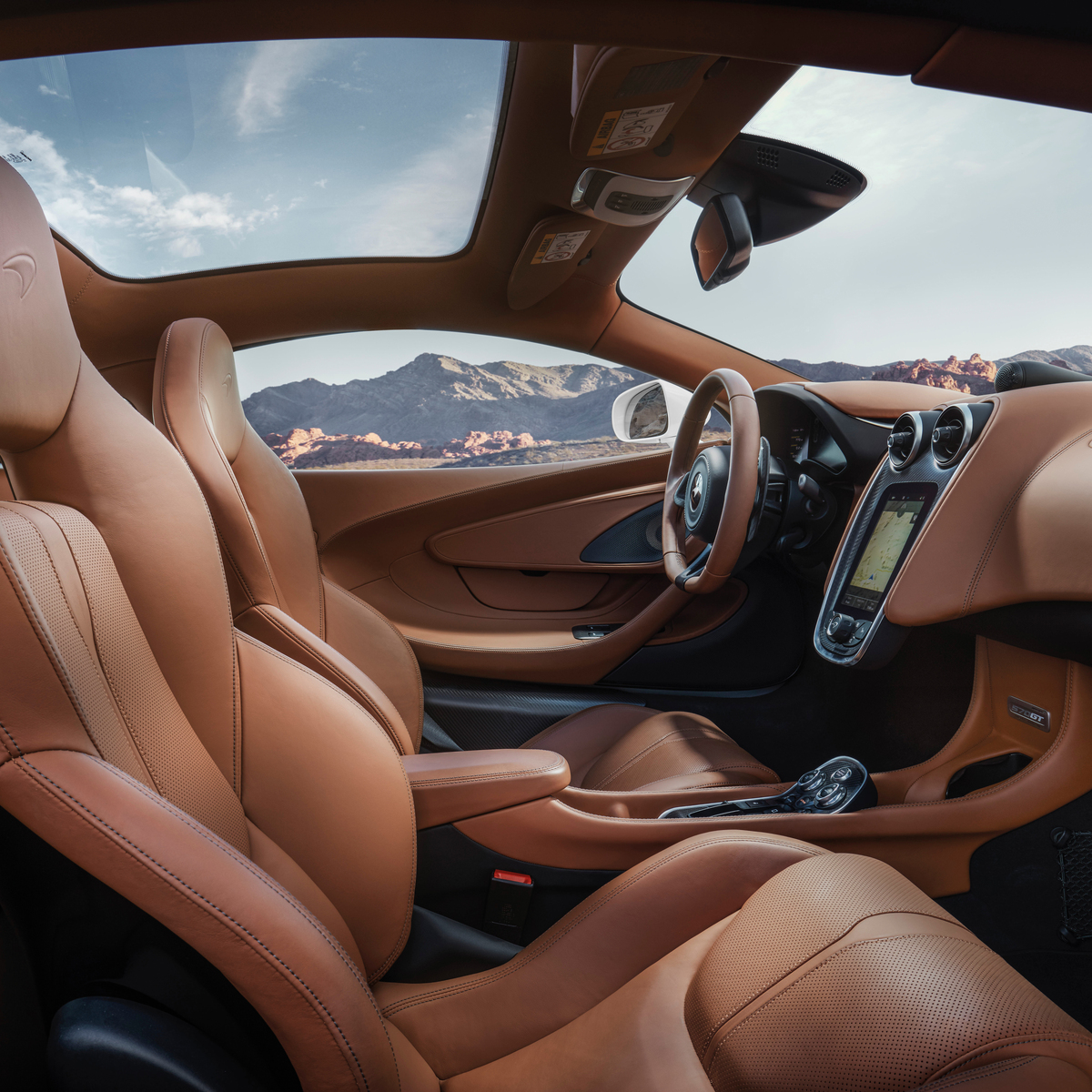 McLaren 570S GT with brown leather interior parked in a desert mountain setting.