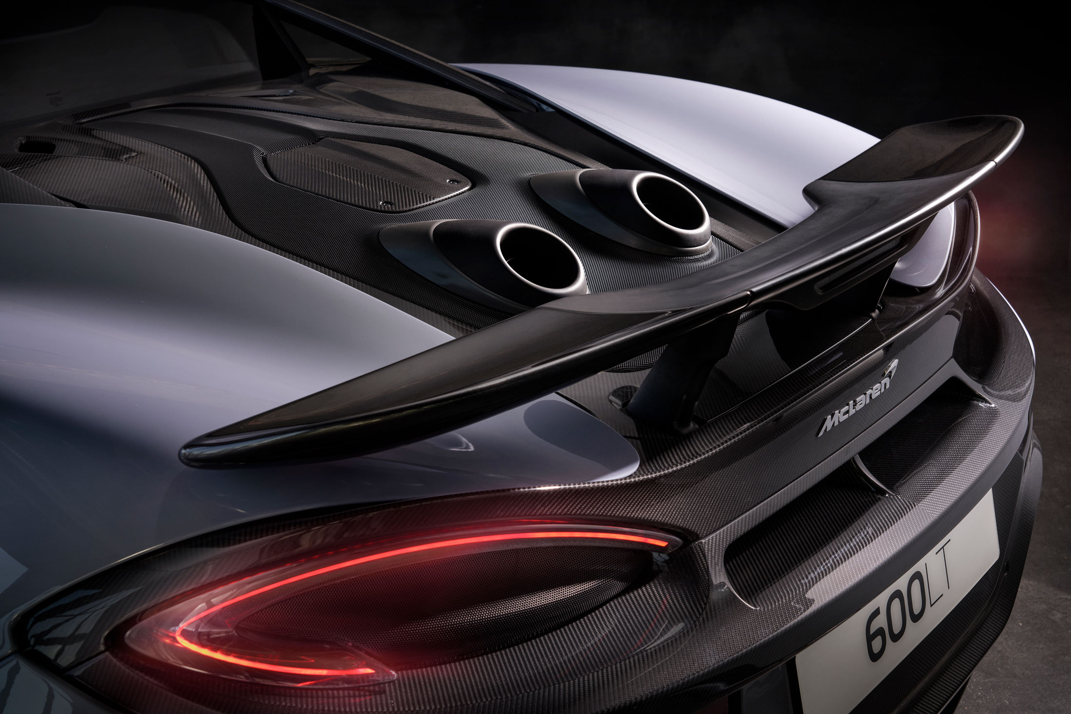 McLaren 600LT rear view showcasing top-exit exhausts, carbon fiber wing, and lightweight aerodynamic design for peak performance