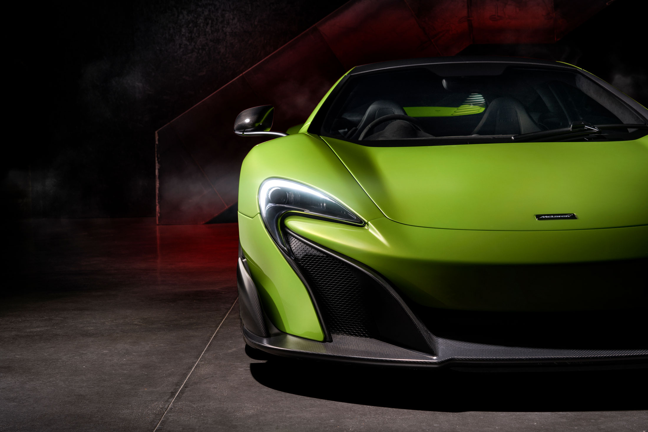 McLaren 675LT in striking green, showcasing its aerodynamics, carbon fiber front splitter, and signature LED headlights