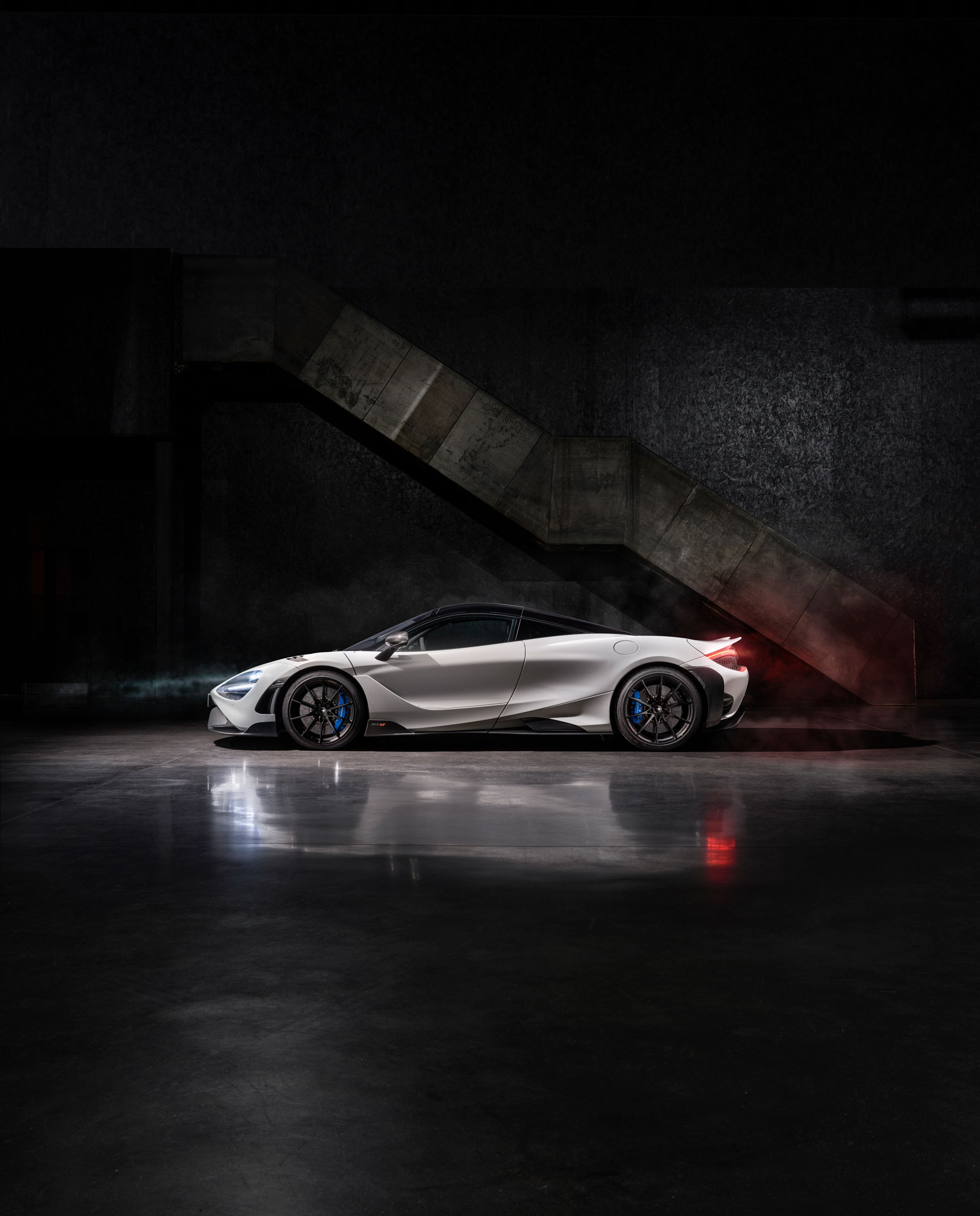 McLaren 765LT in white, captured in profile with carbon fiber aerodynamics and track-focused styling in a dramatic setting
