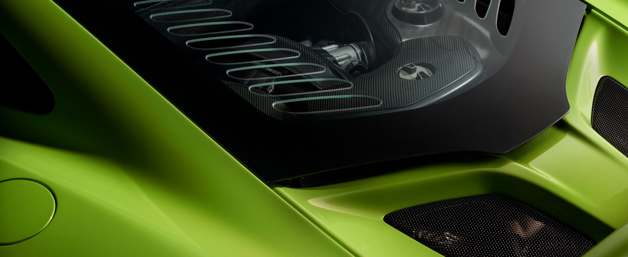 McLaren 675LT engine bay with carbon fiber detailing, visible through lightweight glass cover, showcasing engineering