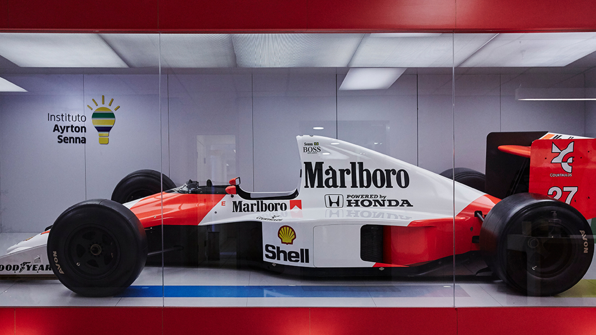 Ayrton Senna's Formula 1 race car in a large glass display case.
