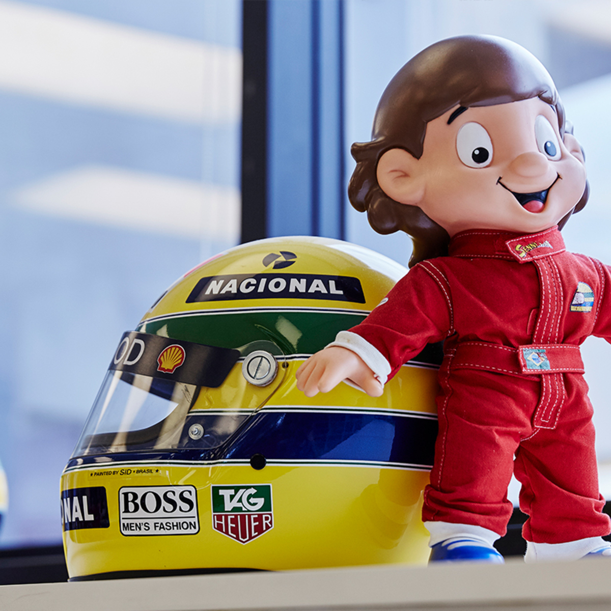 Ayrton Senna helmet and Senninha doll on display.
