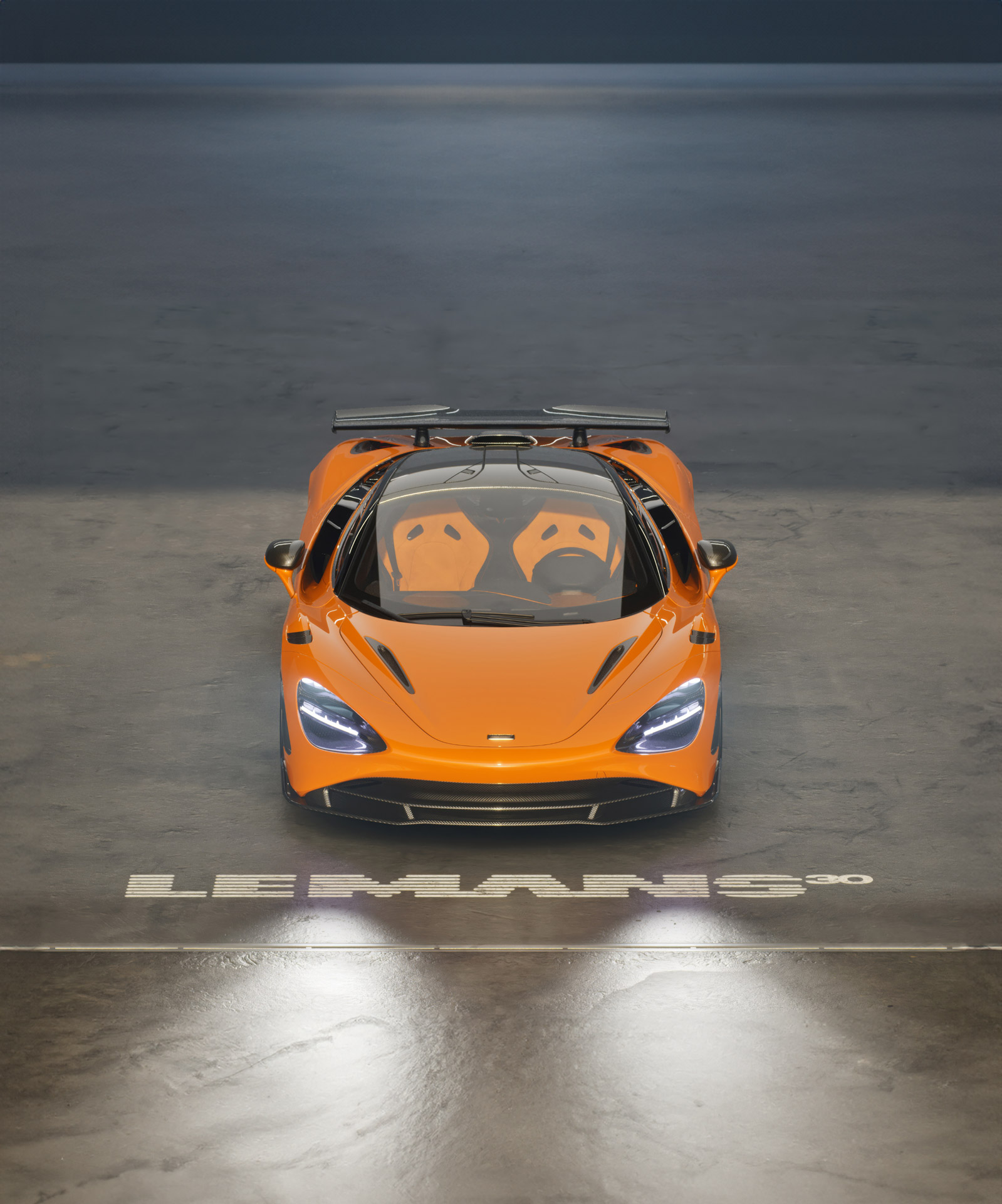 The orange McLaren 750S Le Mans edition viewed from above, with "Le Mans 30" graphics on the floor, commemorating the 30th anniversary of the F1 GTR victory.