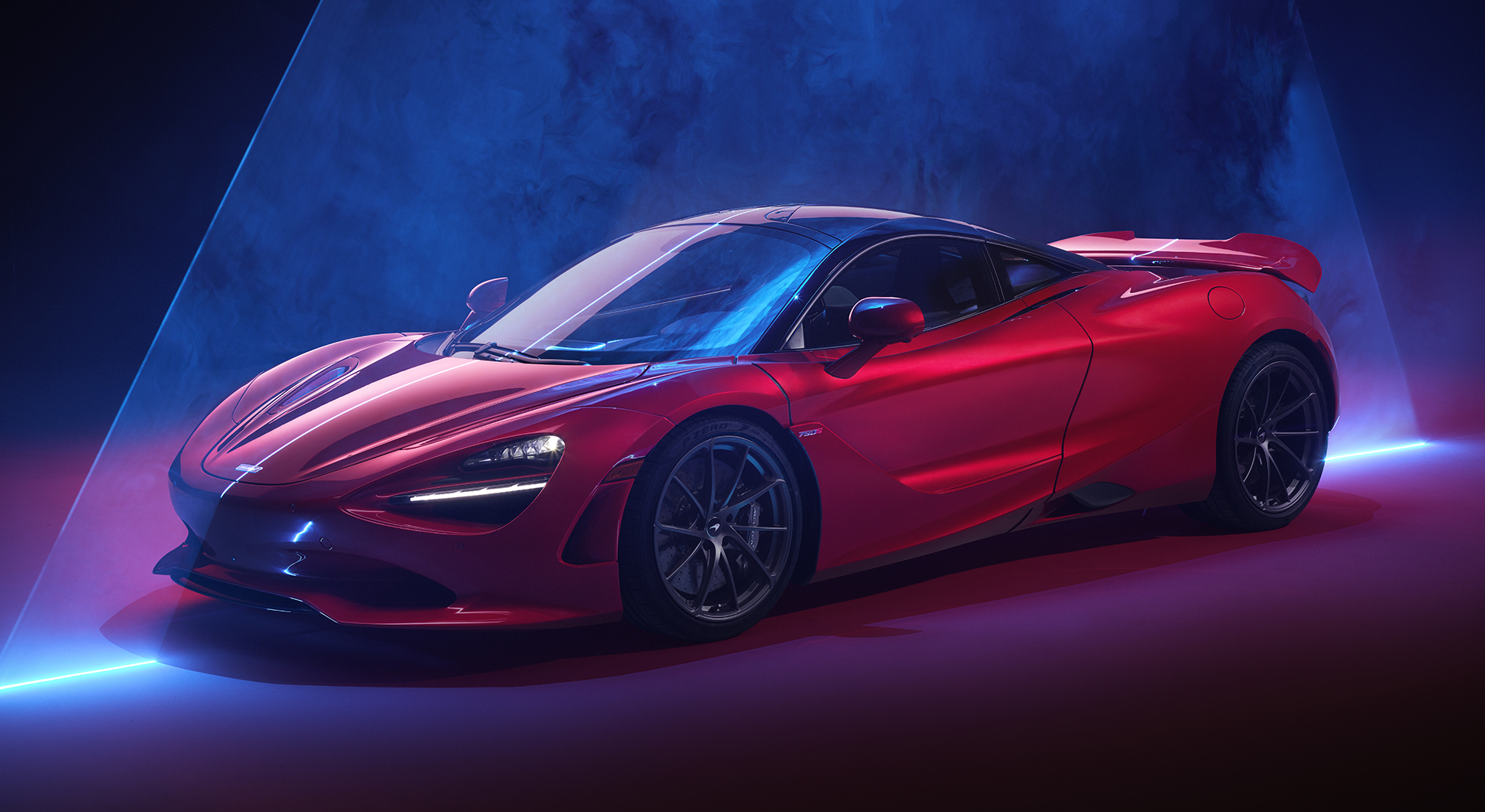 The McLaren 750S in a powerful red finish, with its black roof, in a studio with dramatic lighting and a smoky effect.