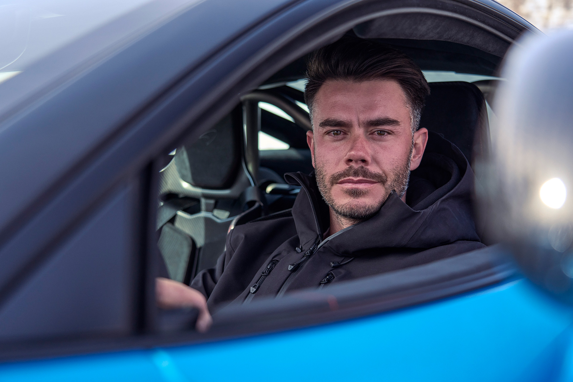 Simon Billy sat in the drivers sear of a blue McLaren 750S, looking straight at the camera through the open window.