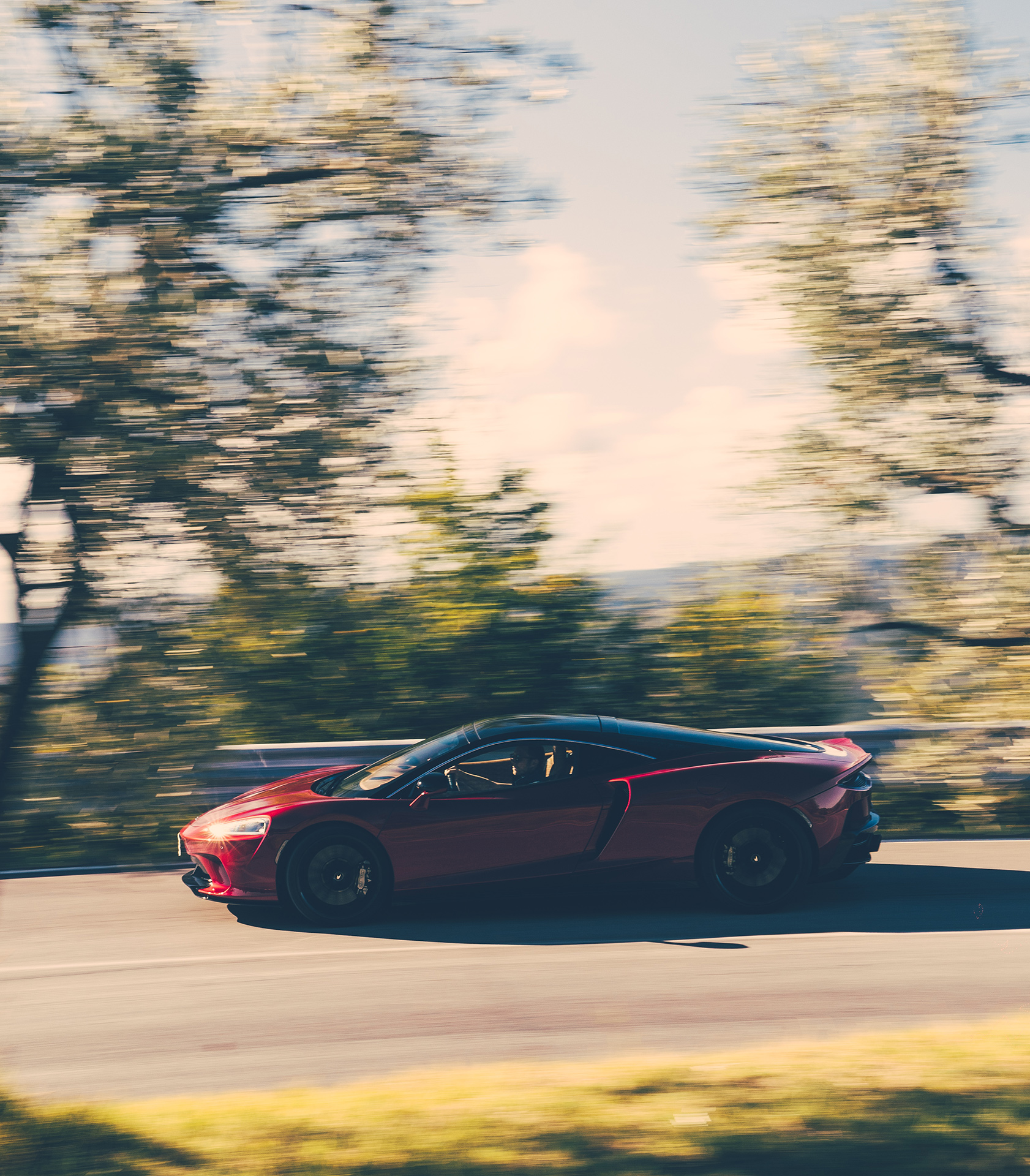 The McLaren GT in a dynamic motion shot, showcasing its grand touring capability and the security of roadside assistance.