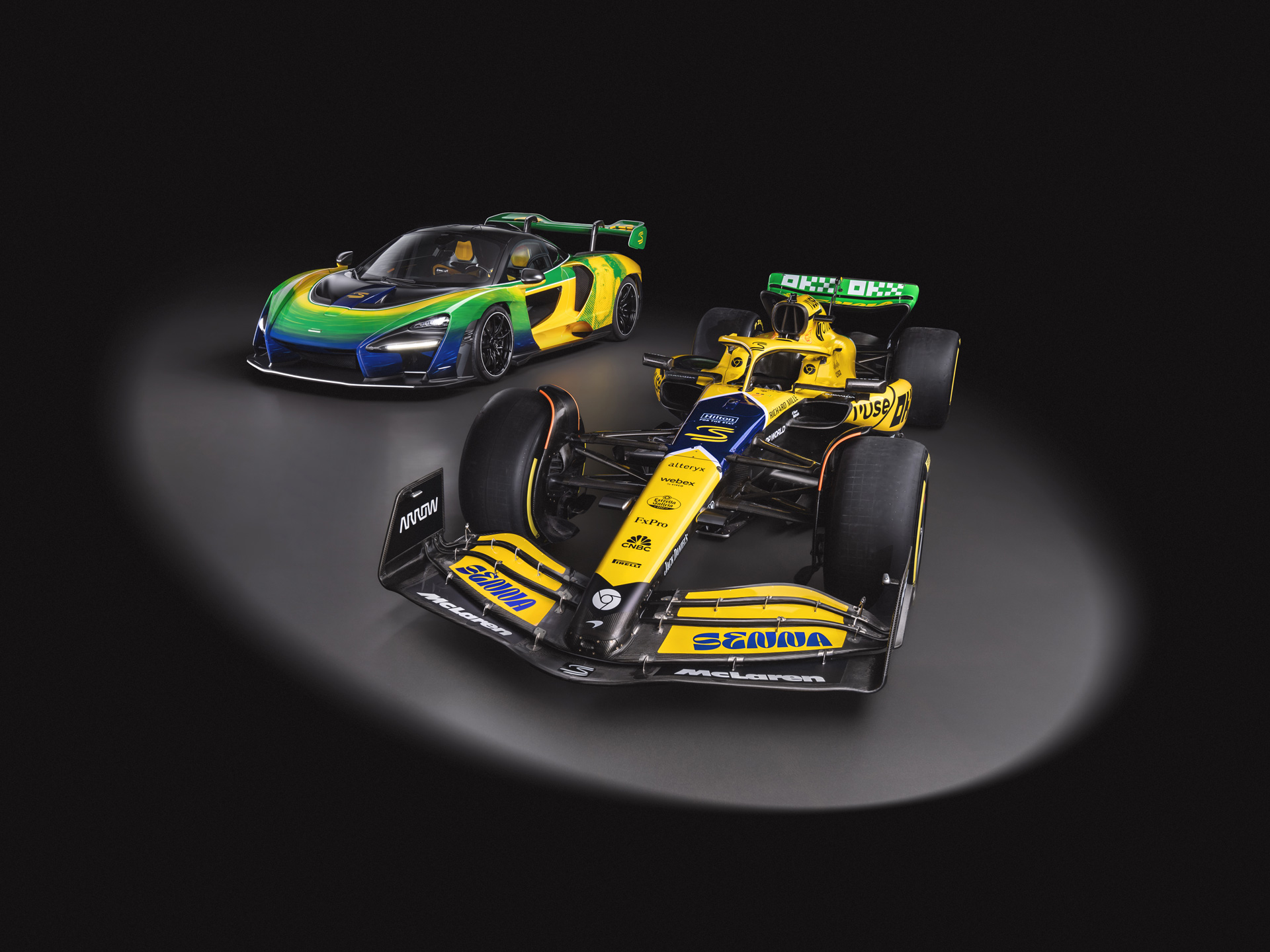 The Senna30 tribute livery McLaren Senna GTR and Formula 1 race car, pictured side by side in a dark studio environment.