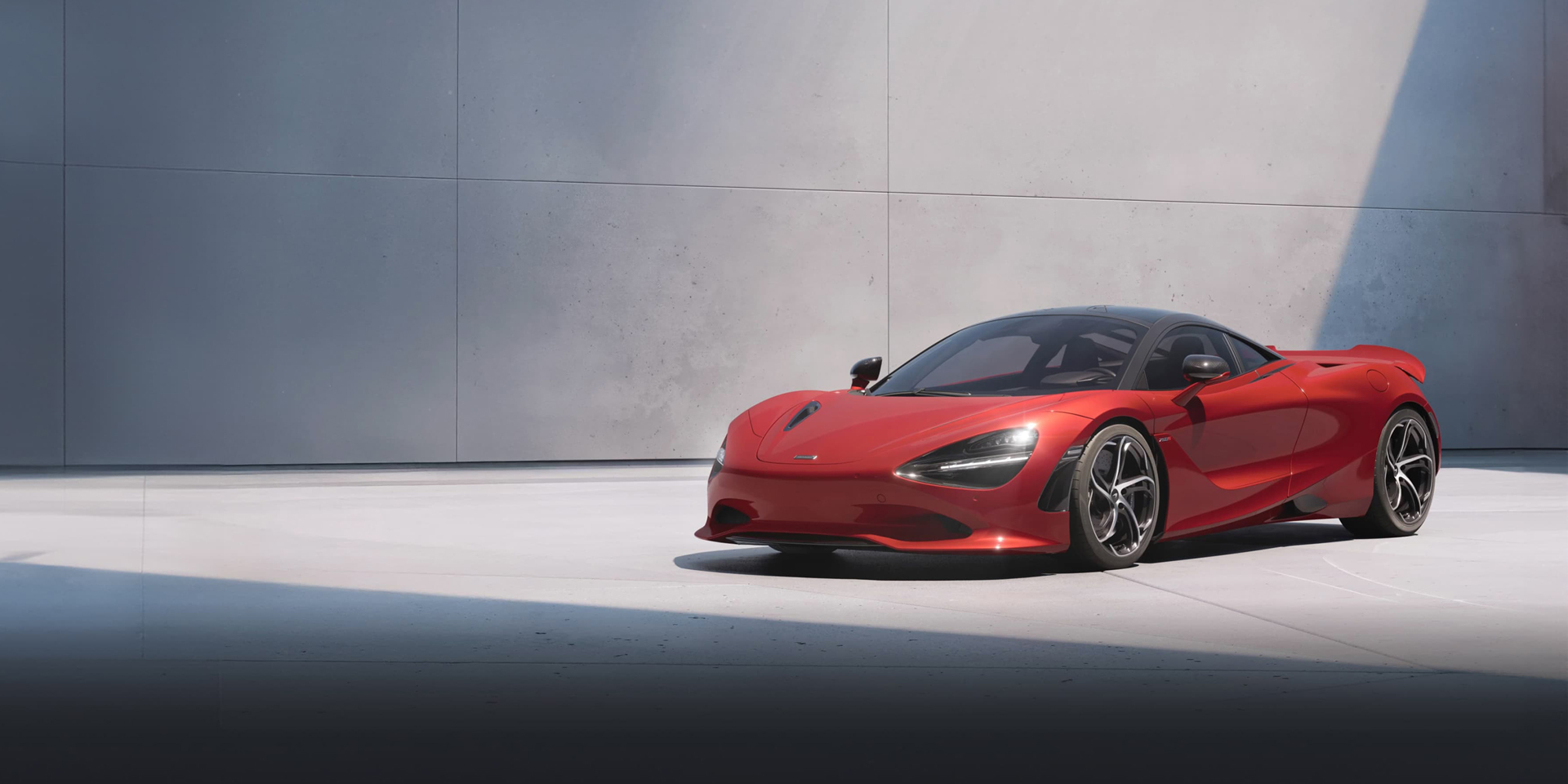 Red McLaren 750S supercar with a black roof and silver wheels, parked indoors.