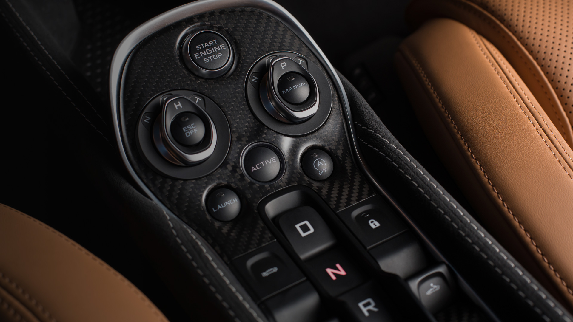 A close-up of a McLaren's carbon fiber center console with controls for the engine, transmission, and launch mode.