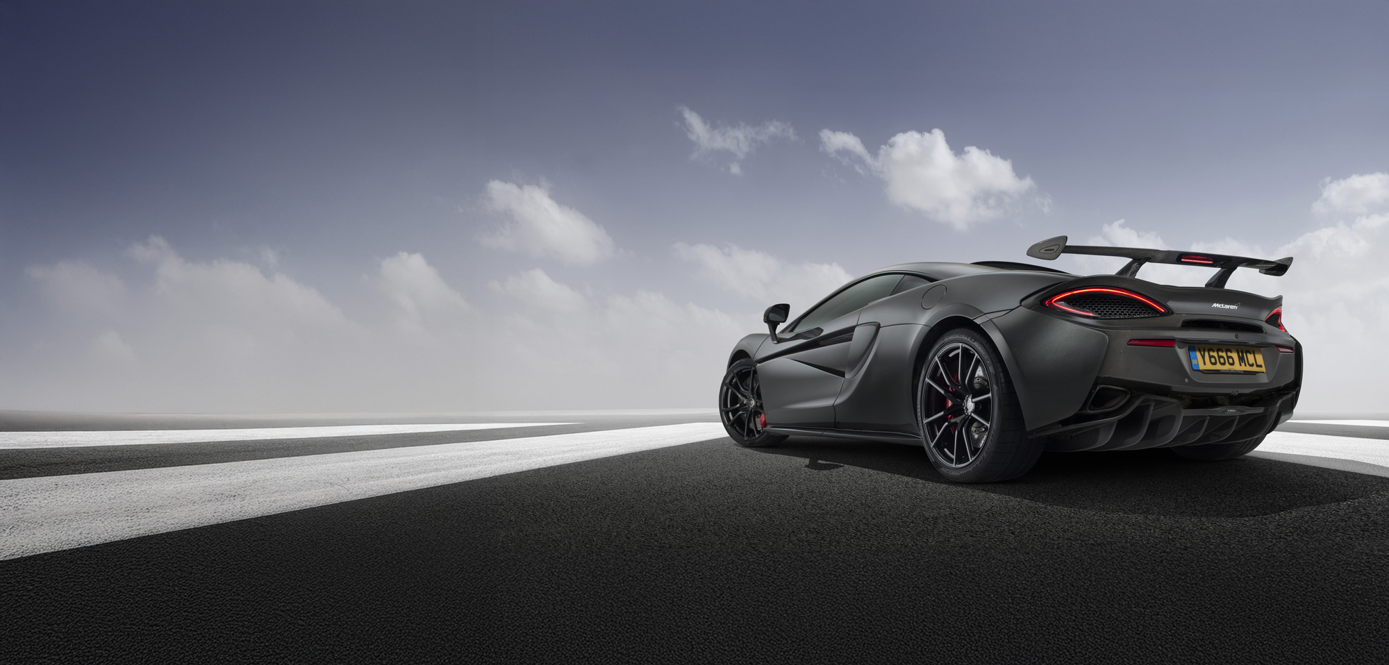 McLaren 600LT in a matte grey finish, showcasing its aggressive rear design, twin exhaust, and large fixed wing.