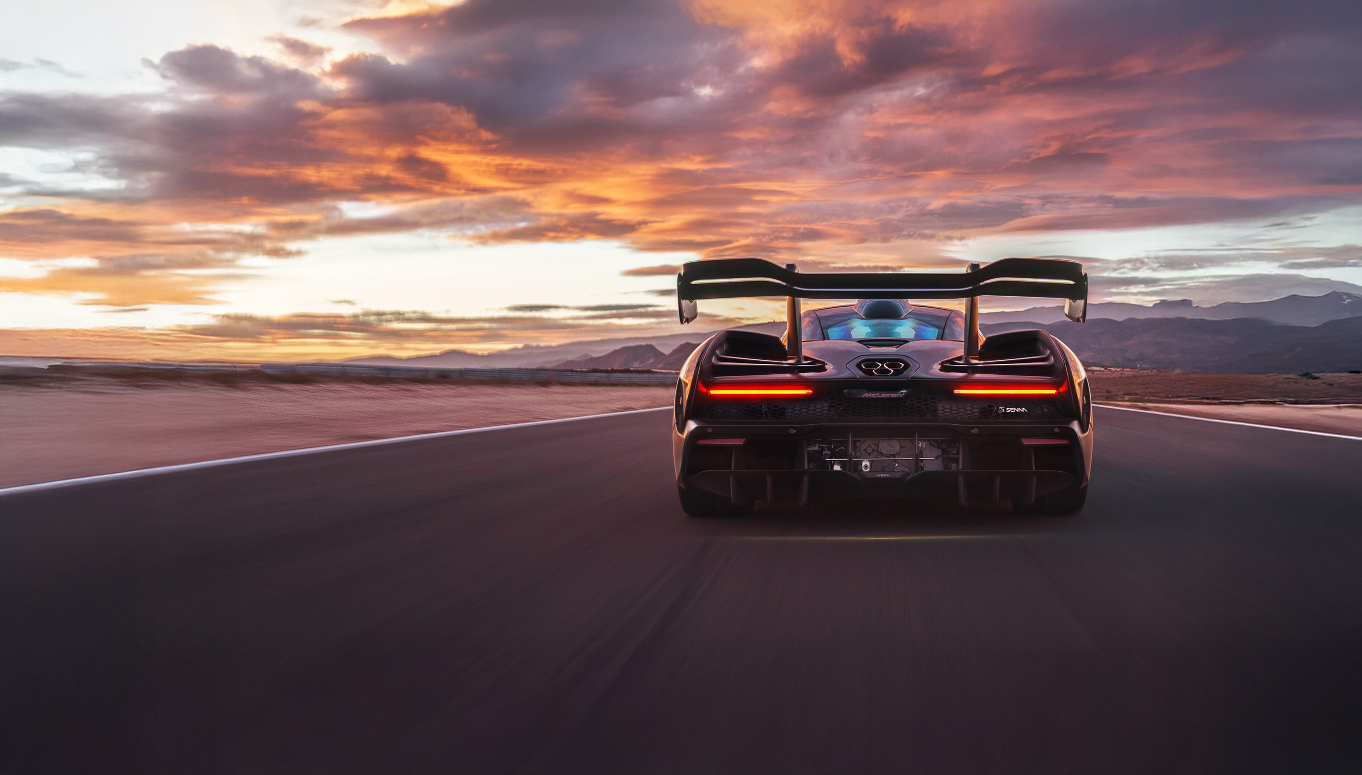 McLaren Senna driving at speed towards some mountains at sunset.