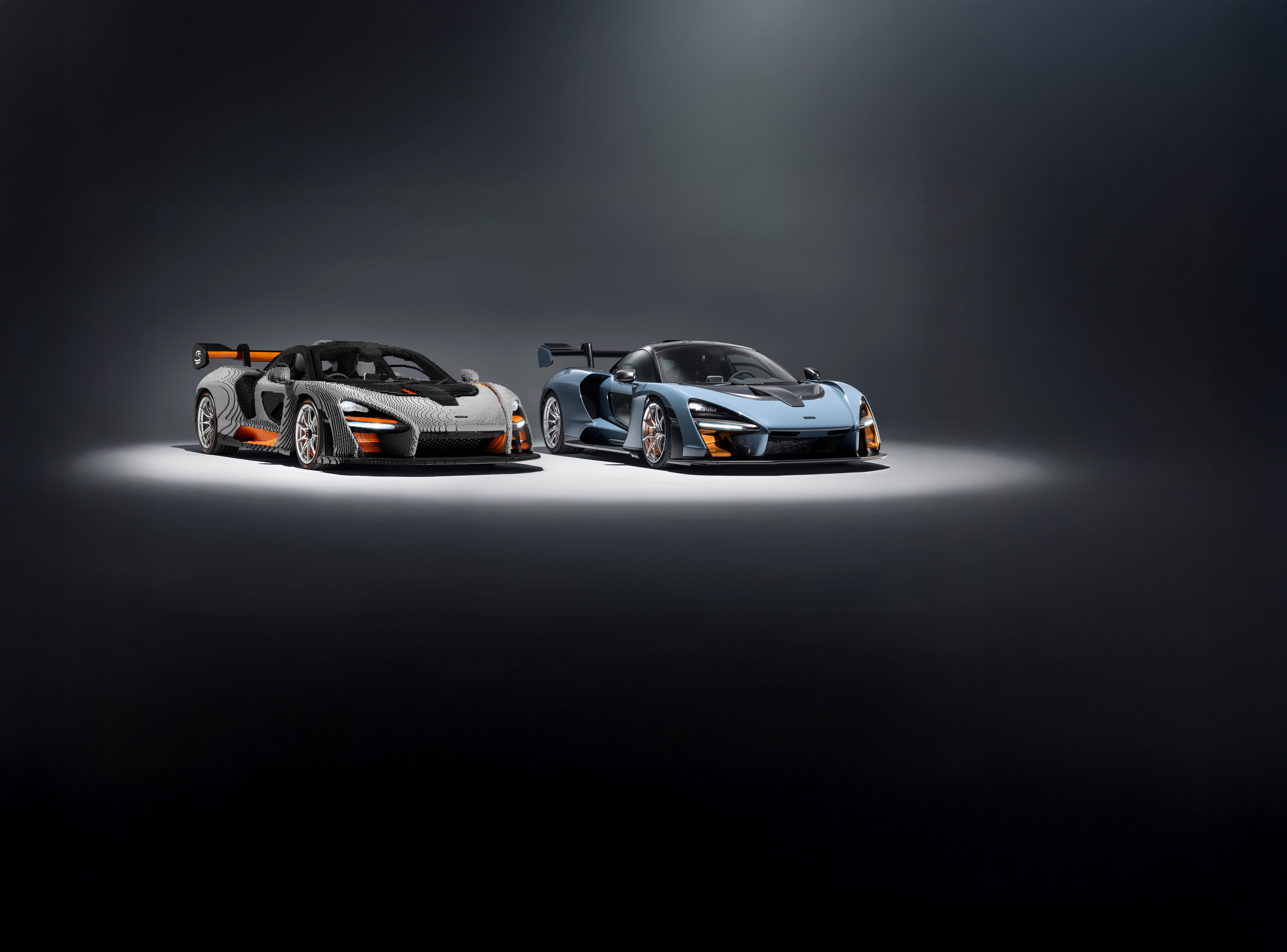 McLaren Senna parked next to its Lego replica, in a grey studio environment.