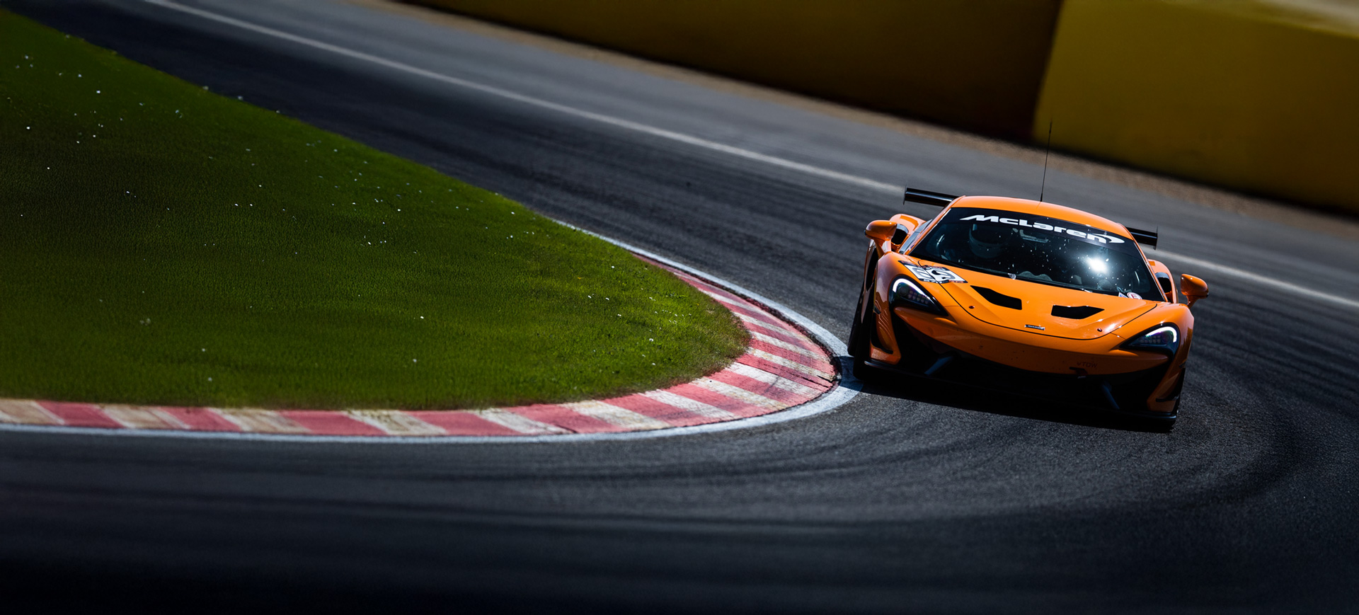 Orange McLaren driving around a track at speed.