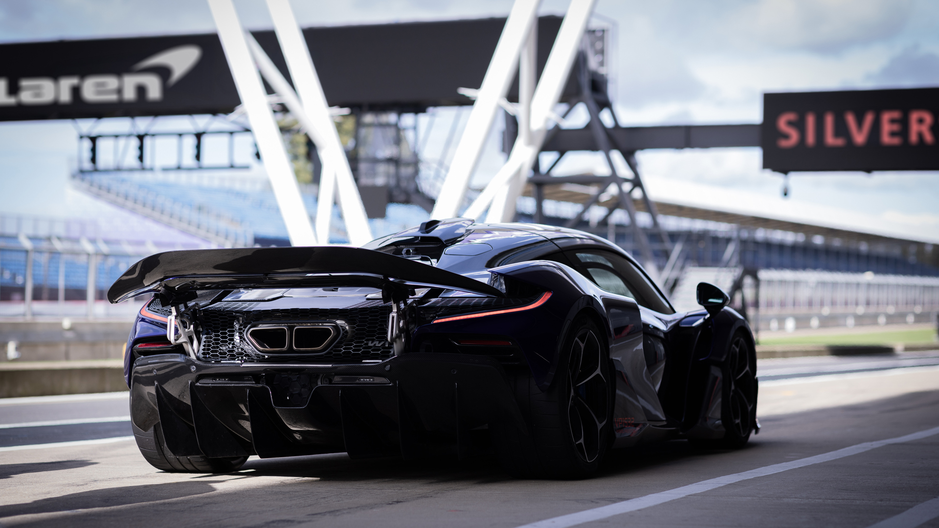 A shot of the tail end of the McLaren W1 parked on the Silverstone track with a McLaren sign above.