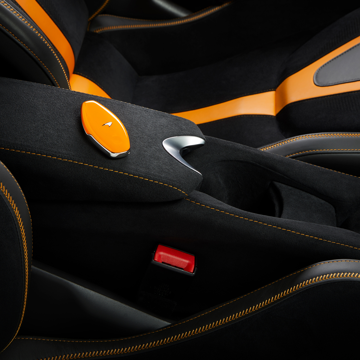 A close-up shot of the interior of a McLaren, focusing on the centre console and seat upholstery. 
