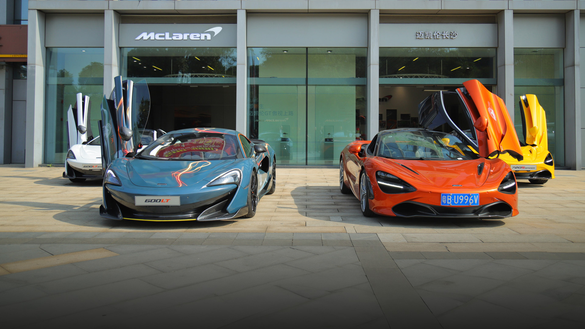 McLaren Changsha official retailer exterior in China, featuring a display of high-performance supercars with dihedral doors open.