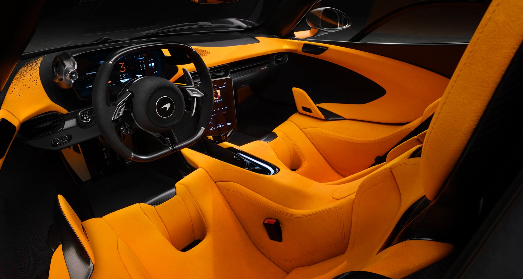 A detailed interior shot of the McLaren W1 showing bright orange bucket seats, a minimalist dashboard, and a sporty steering wheel.