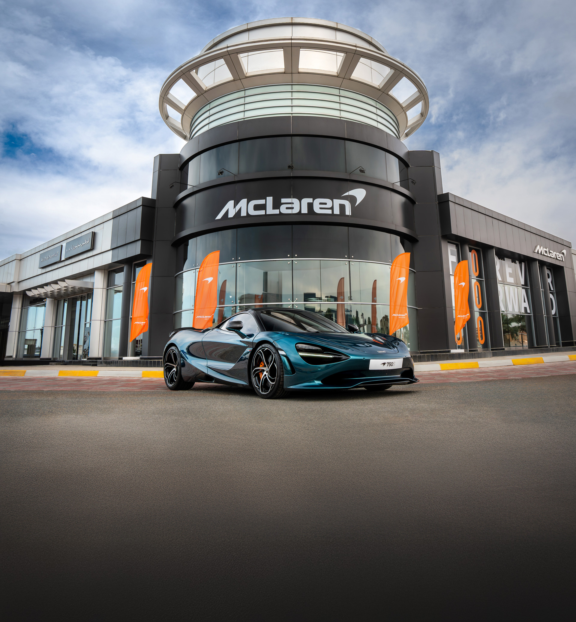 A metallic blue McLaren 750S parked outside the McLaren Abu Dhabi retailer storefront. 