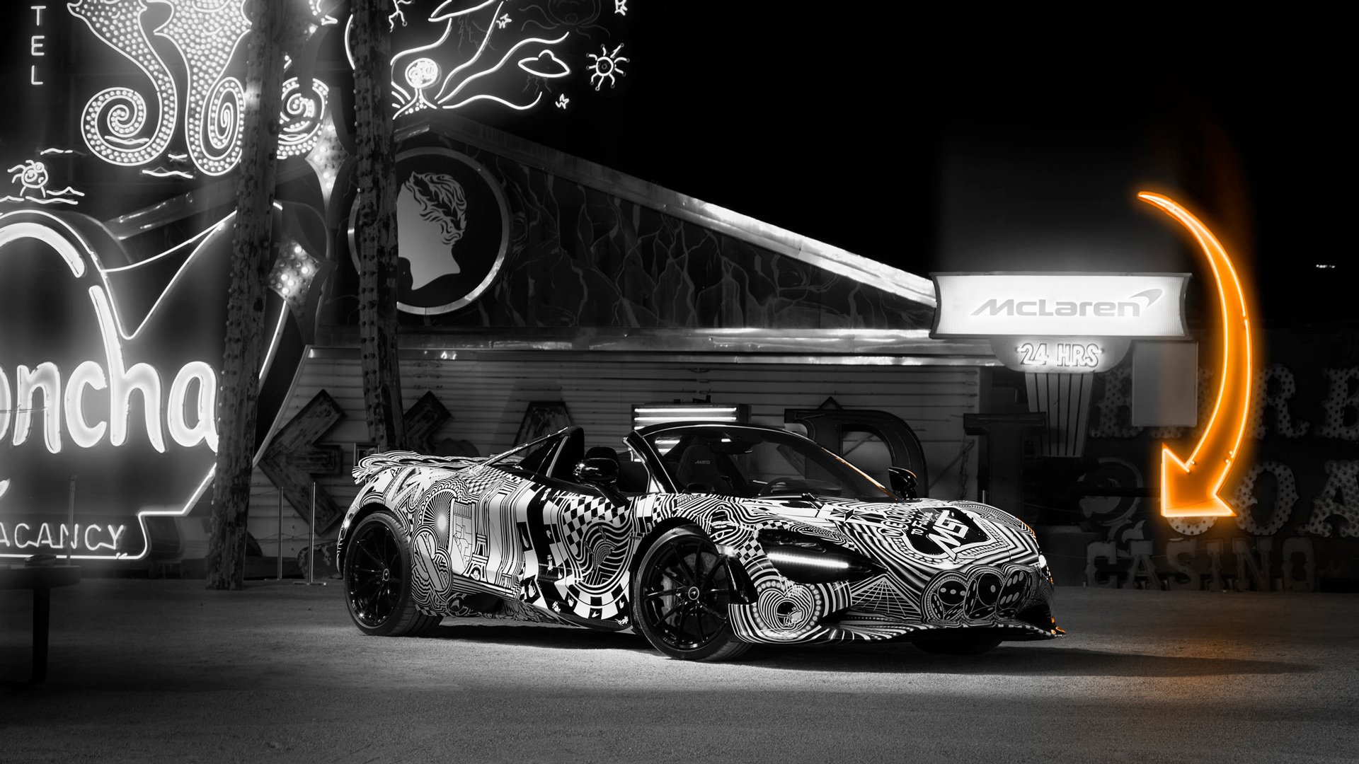 The McLaren 750S Spider 'Project Viva' parked in front of classic neon signs in Las Vegas, showcasing the MSO car's black-and-white casino-themed livery.
