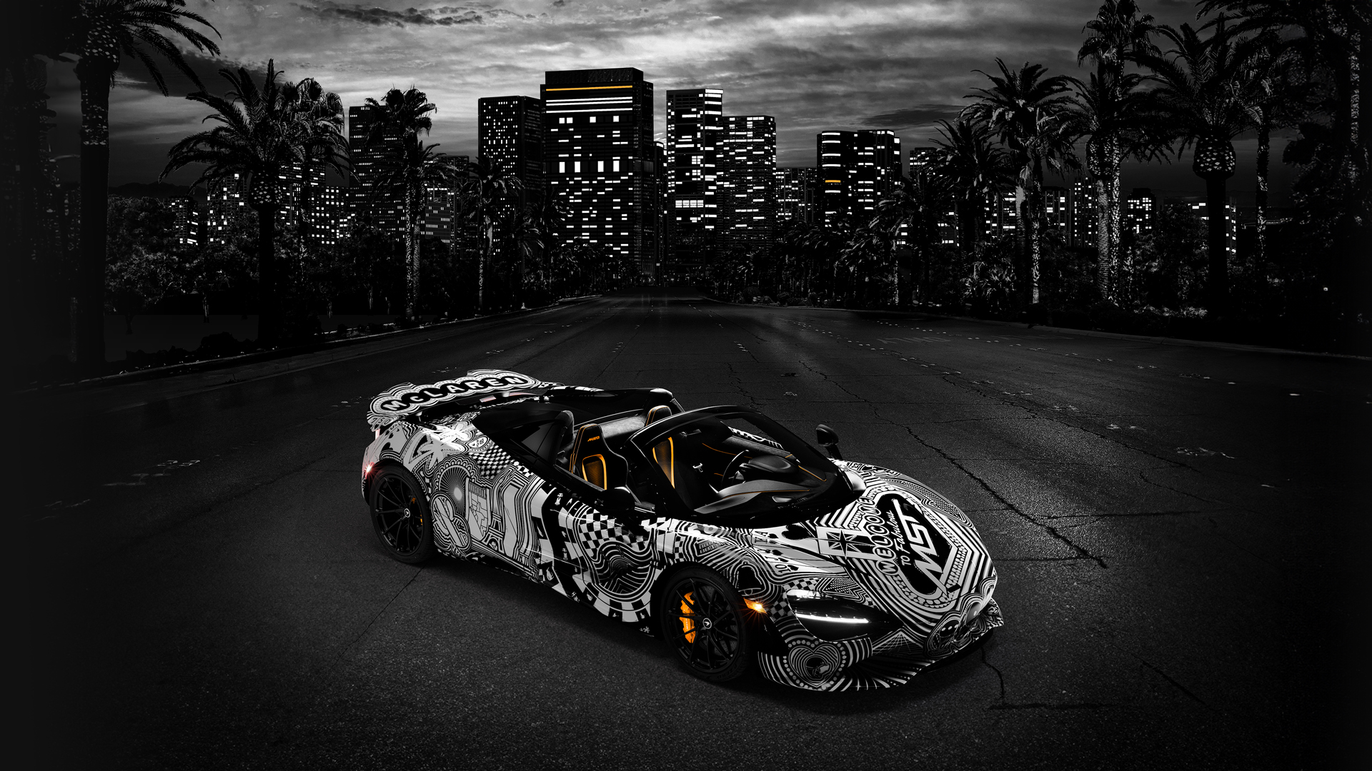Full-body view of the McLaren 750S Spider 'Project Viva' driving on a dark road in front of the Las Vegas skyline, emphasizing the striking monochrome, custom-painted MSO livery