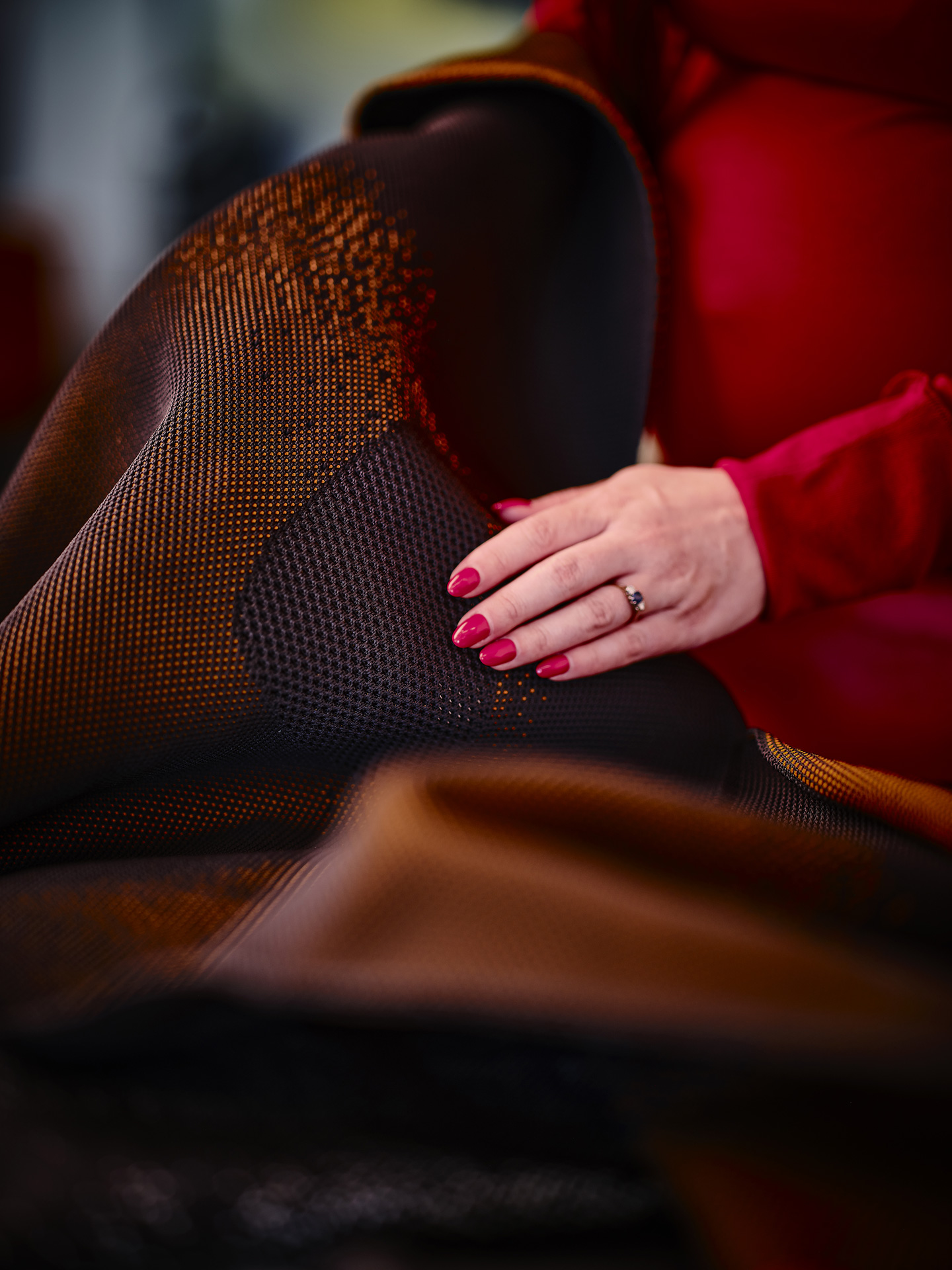 The McLaren InnoKnit textile being shown by a female employee wearing a red dress.