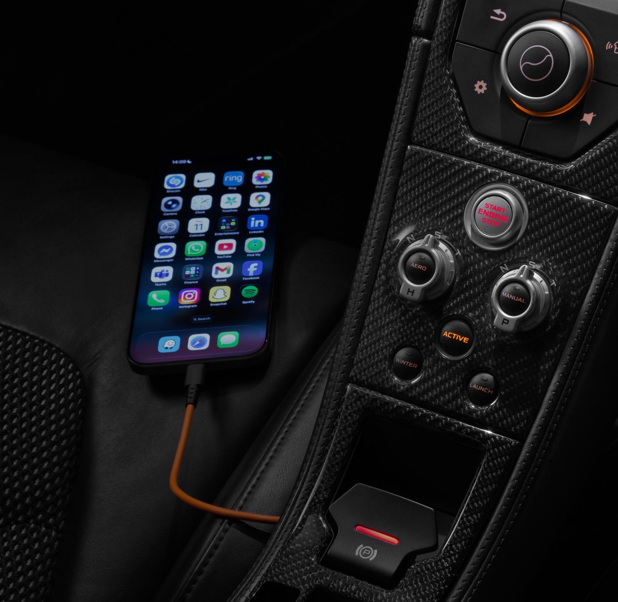 Apple CarPlay screen shown within the centre console of a McLaren Supercar with a iPhone plugged into the left.