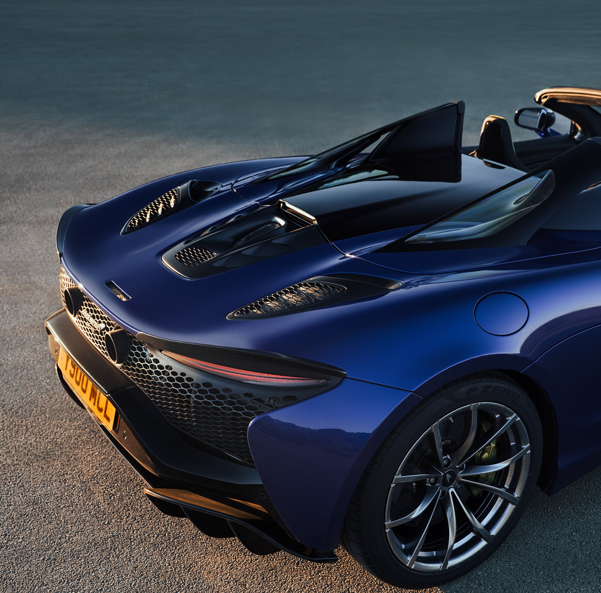 A high view shot of the McLaren Artura Spider with its roof down parked on a gravel driveway.