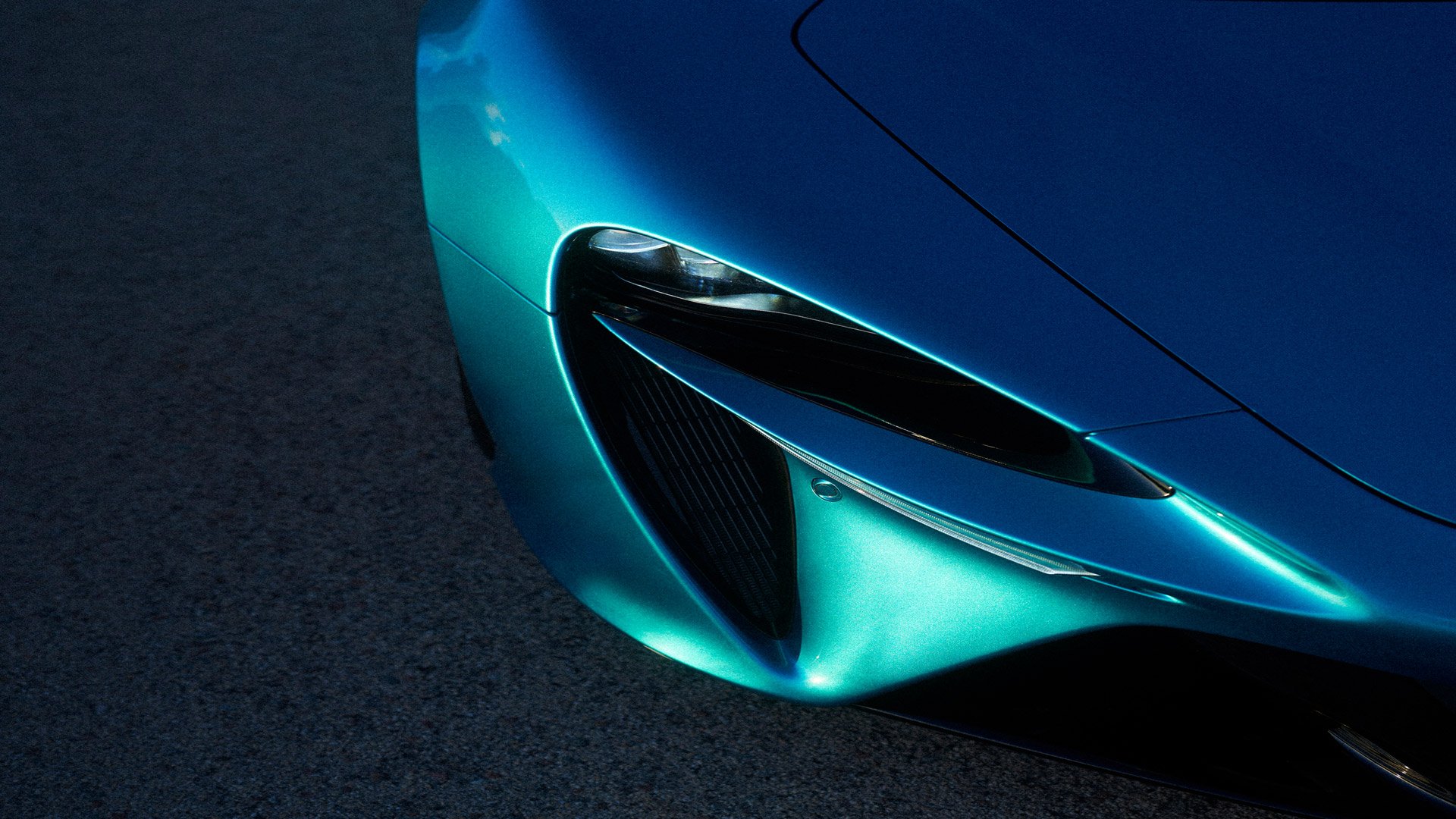 Overhead photograph of the front left headlight of a blue McLaren Artura Coupe
