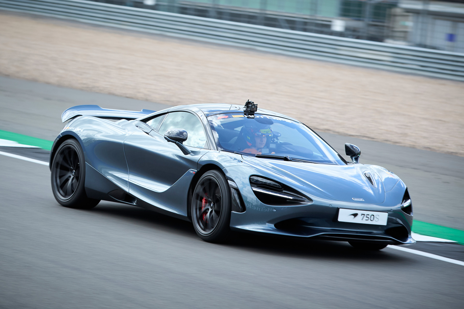  Silver McLaren 750S supercar with a driver on a racetrack, captured at speed.