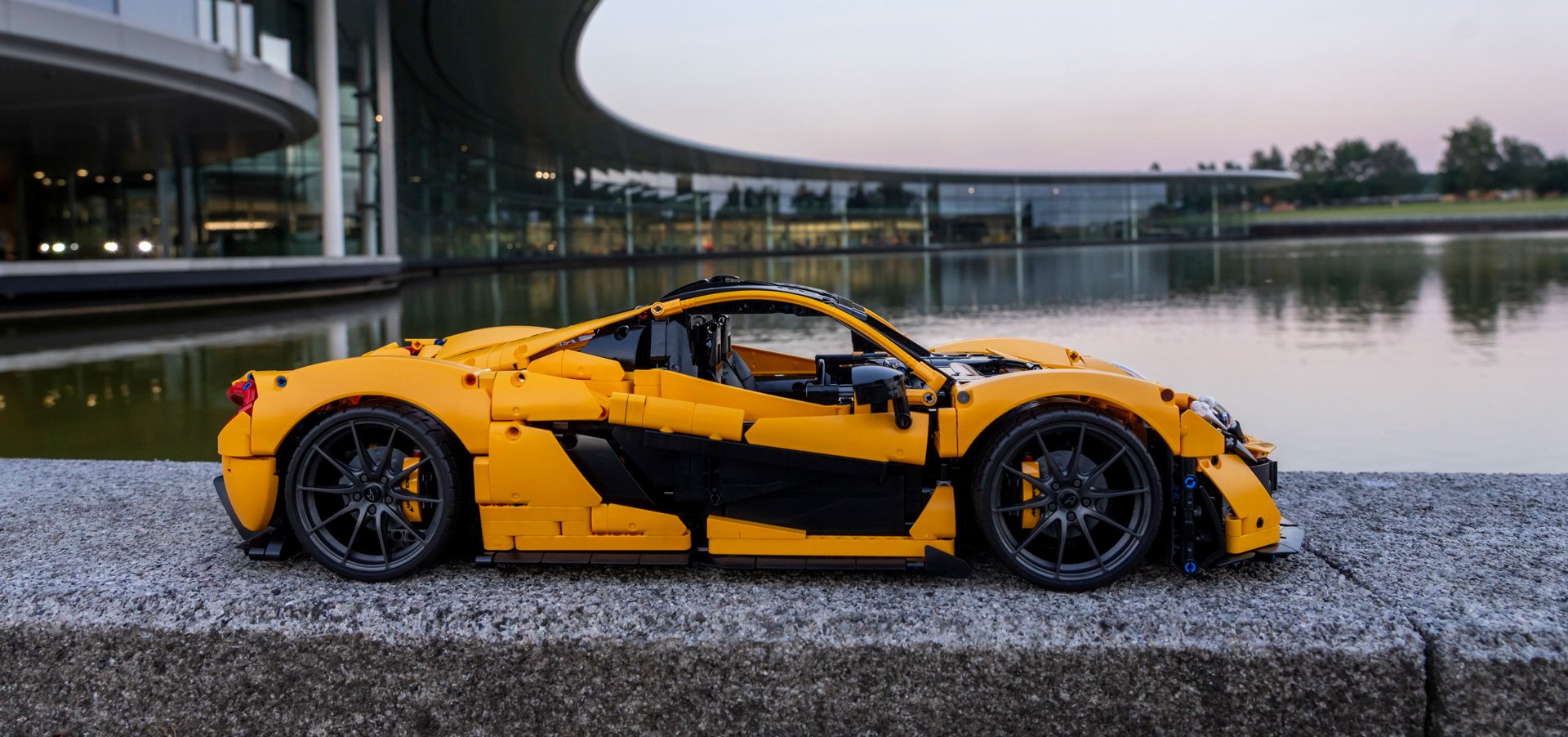 Yellow lego McLaren replica, parked in front of the McLaren Technology Centre.