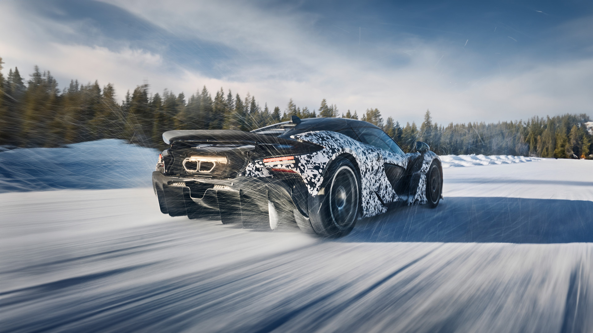 A low-angle rear view of a camouflage-wrapped McLaren W1 prototype speeding across a snow-covered expanse, kicking up a spray of snow behind it.