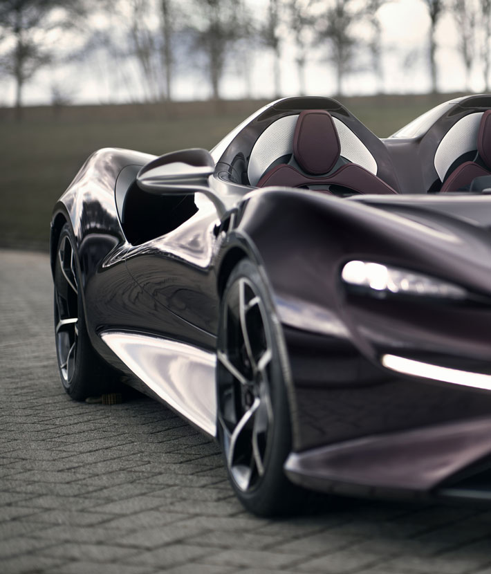A close-up side view of a dark purple McLaren Elva supercar with its headlights on.