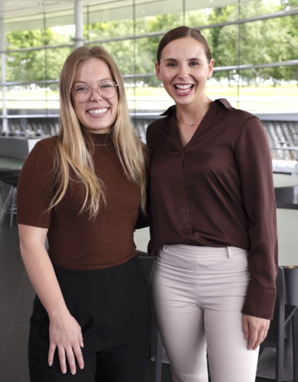 Two happy female McLaren employees smiling and posing for a photo.